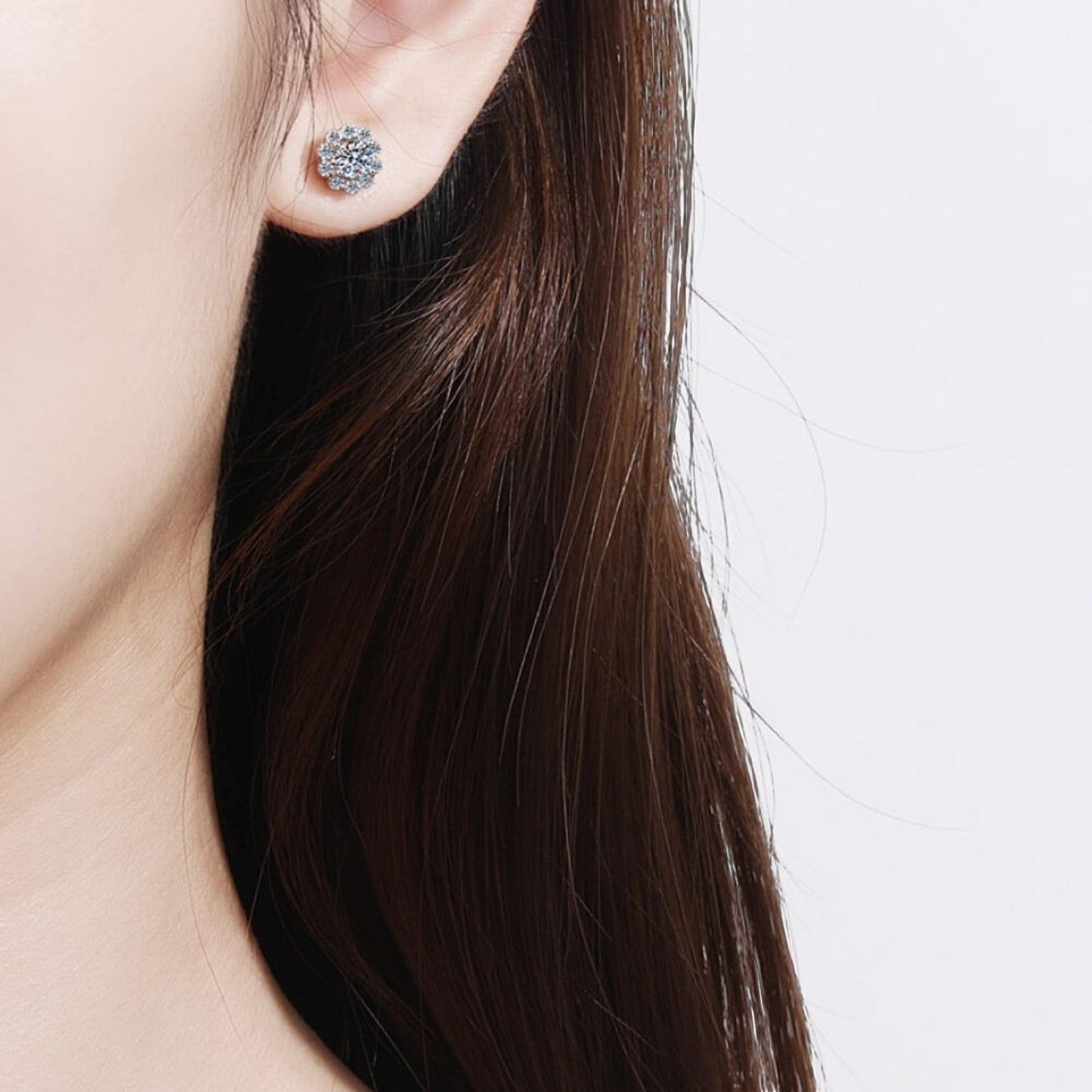 Sfeerfoto van een model die het zilveren ModaMelhor bloemvormige oorknopje met moissanite en zirkonia accenten elegant in het oor draagt.