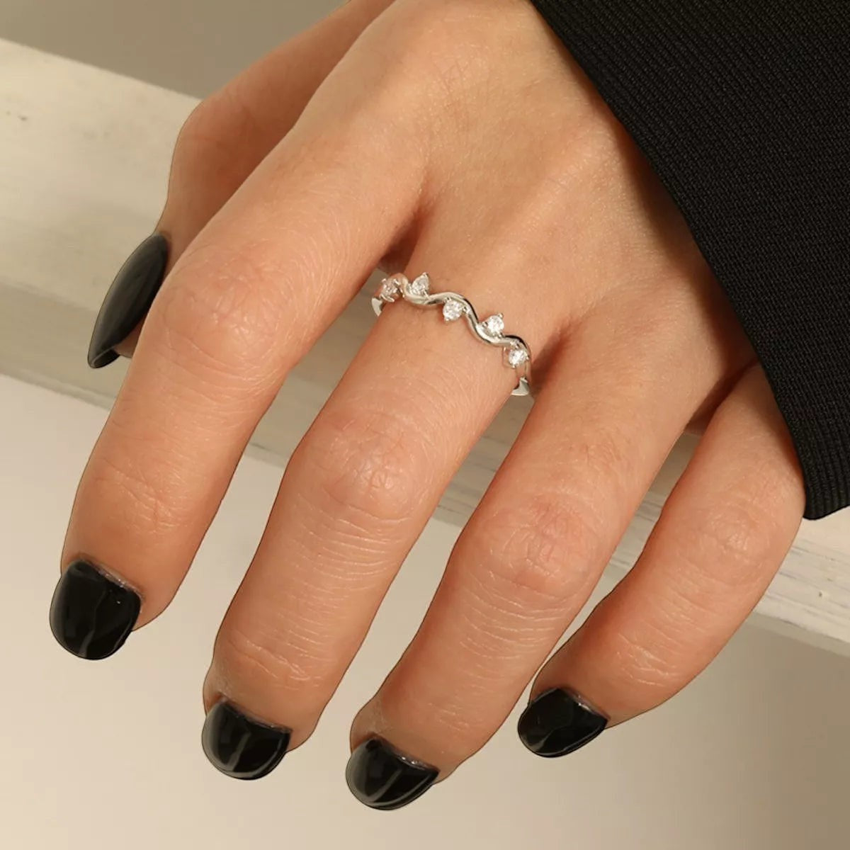 Sfeerfoto van de hand van een model die de zilverkleurige ModaMelhor ring van 925 sterling zilver met golvend patroon en zirkonia steentjes elegant draagt.