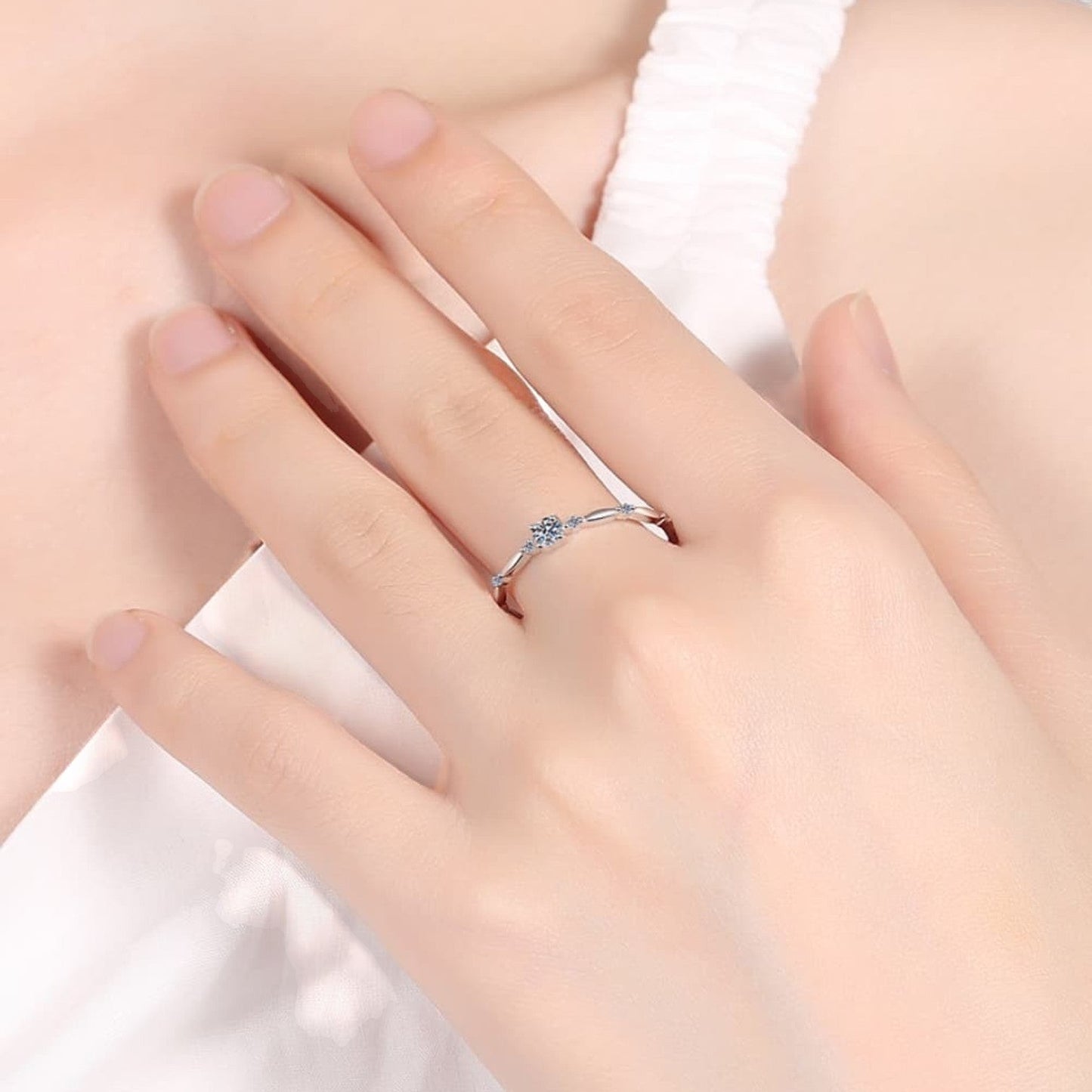 De hand van een model die de verfijnde ModaMelhor zilveren solitair ring met een 0,1 karaat moissanite elegant draagt.