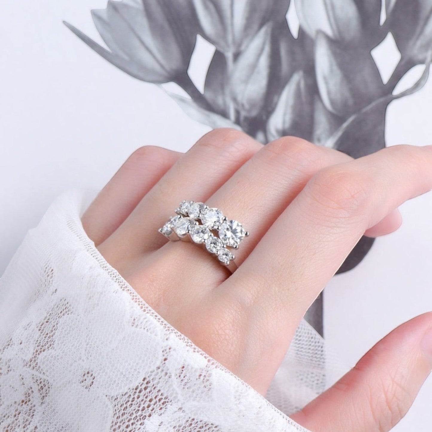 De hand van een model die de ModaMelhor zilveren statement ring met een luxe, dubbele rij van moissanite stenen elegant draagt.