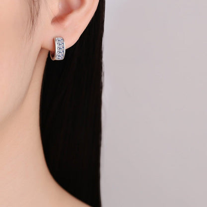 Zijaanzicht van een model dat de zilveren ModaMelhor 1.8 karaat baguette moissanite huggie oorbel met een strakke kanaalzetting in het oor draagt.