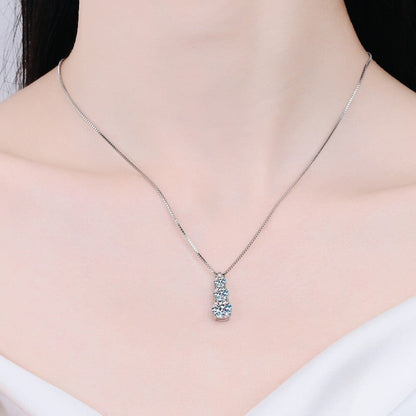 Vooraanzicht van een model dat de zilverkleurige ModaMelhor 925 sterling zilveren ketting met de verticale driestenen moissanite hanger om de hals draagt.