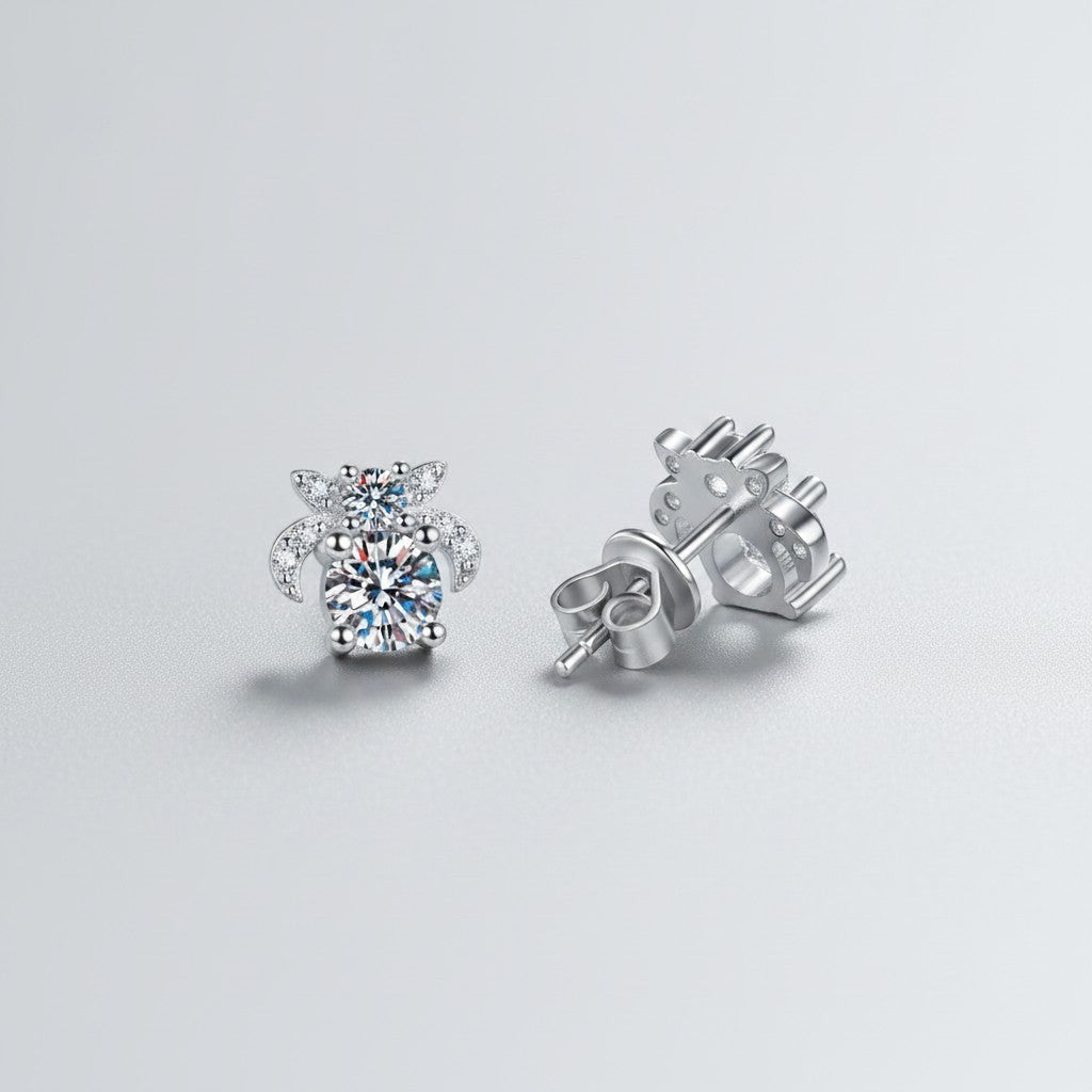 Schuinaanzicht van de ModaMelhor moissanite oorbellen van 925 sterling zilver, waarbij één sieraad van voren en één sieraad met de achterkant en de vlindermutssluiting wordt getoond.