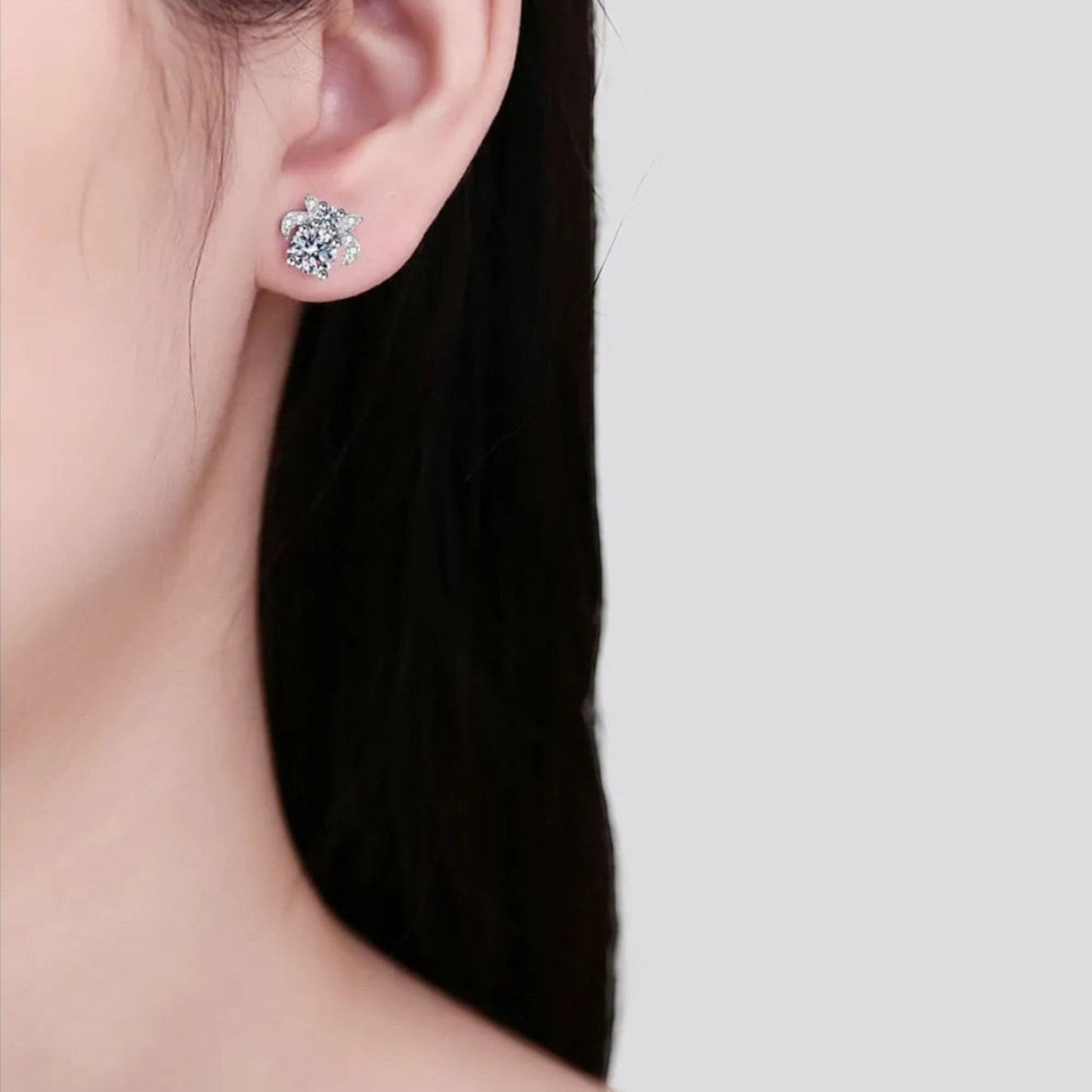 Zijaanzicht van een model dat de Zijaanzicht van een model dat de zilverkleurige ModaMelhor 925 sterling zilveren moissanite oorbel met het vlinder-ontwerp in het oor draagt.