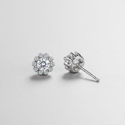 Vooraanzicht en zijaanzicht van de platliggende ModaMelhor bloemvormige oorbellen van 925 sterling zilver met een centrale moissanite steen en zirkonia accenten.