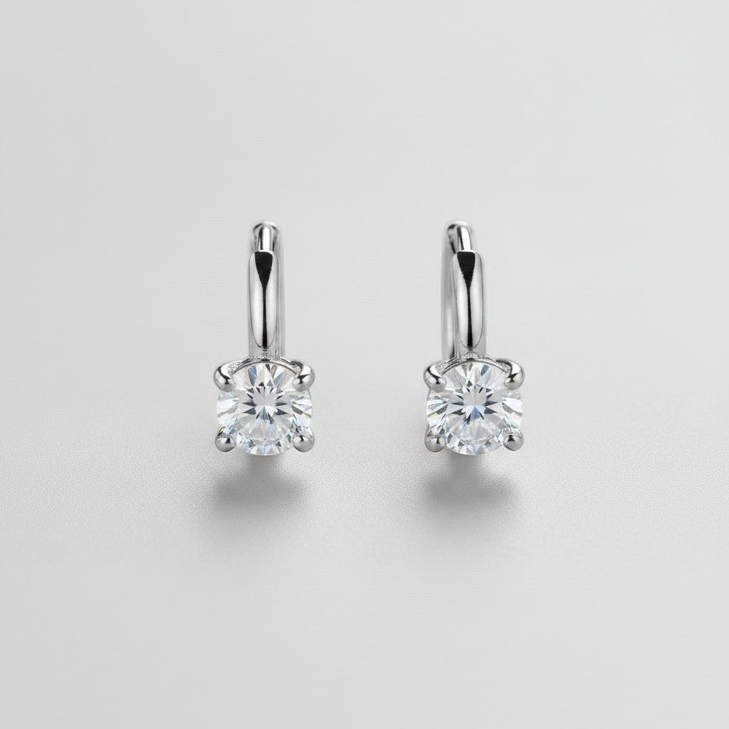 Symmetrisch vooraanzicht van het paar rechtopstaande ModaMelhor huggie oorbellen van 925 sterling zilver met ronde, briljant geslepen moissanite stenen.