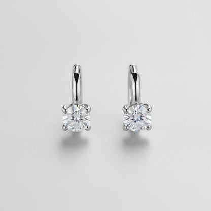 Symmetrisch vooraanzicht van het paar rechtopstaande ModaMelhor huggie oorbellen van 925 sterling zilver met ronde, briljant geslepen moissanite stenen.