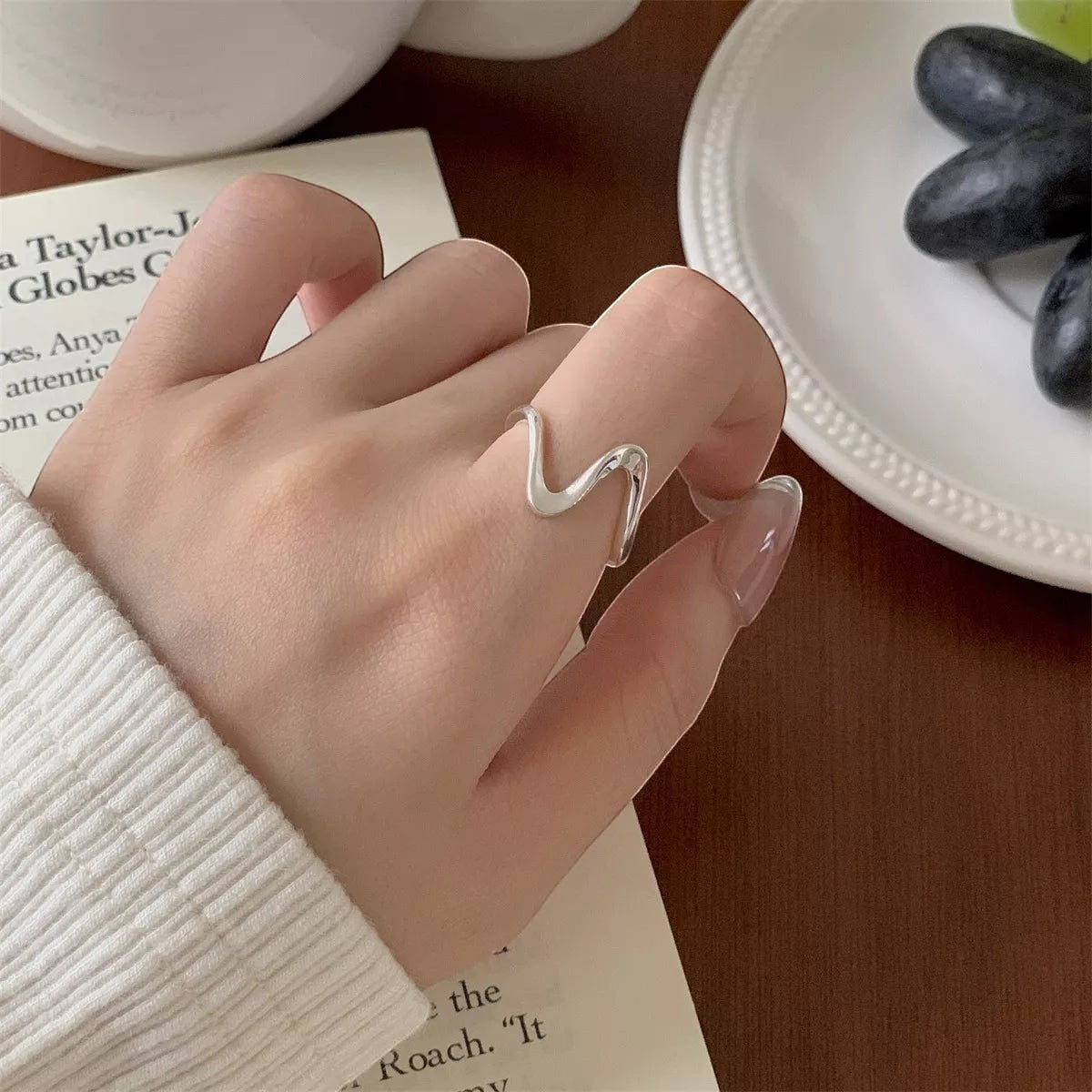 Sfeerfoto van de hand van een model die de zilveren ModaMelhor ring met het unieke, diep gebogen curved ontwerp elegant om de wijsvinger draagt.