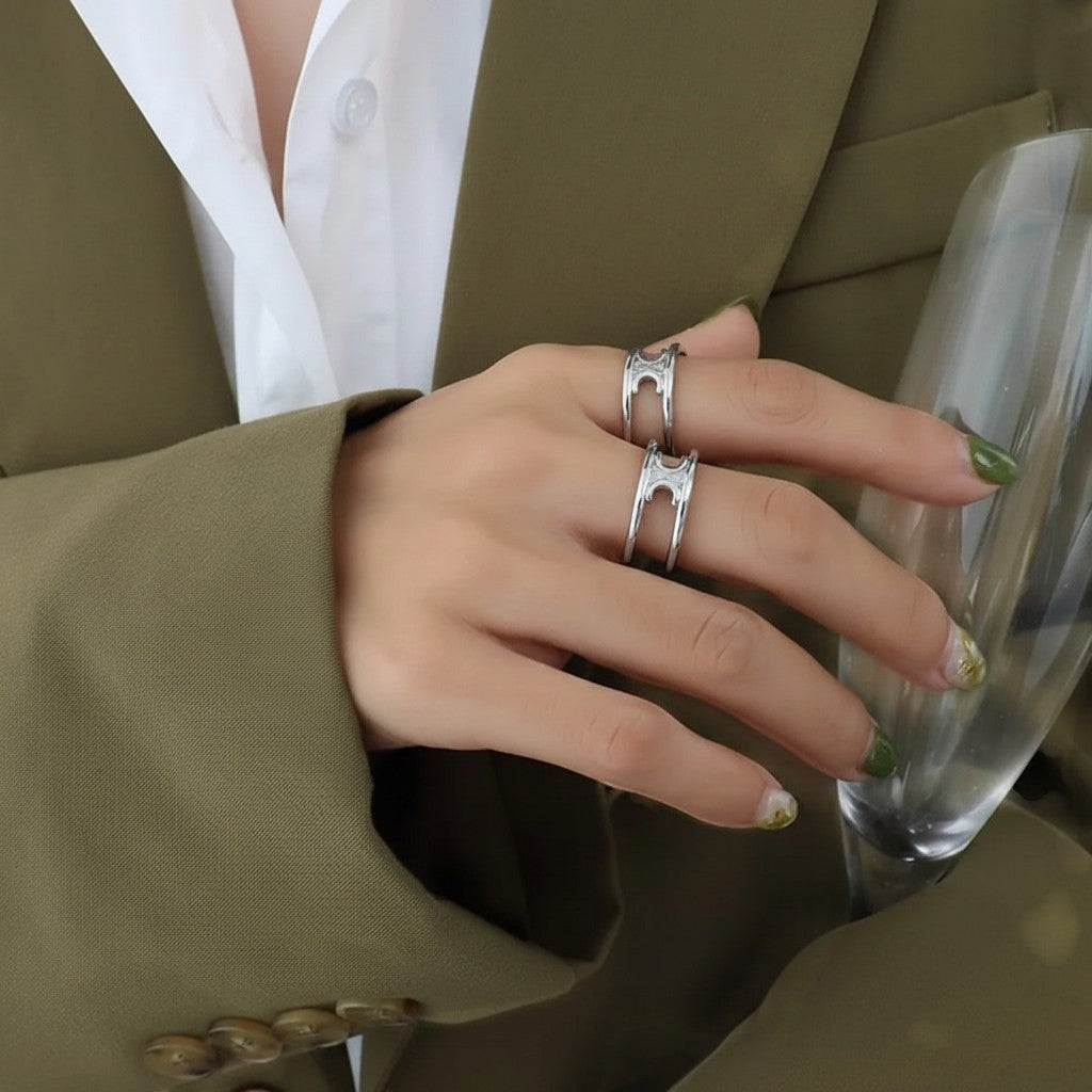 De hand van een model die de zilverkleurige ModaMelhor open ring van titanium staal met het dubbele bandenontwerp elegant draagt.
