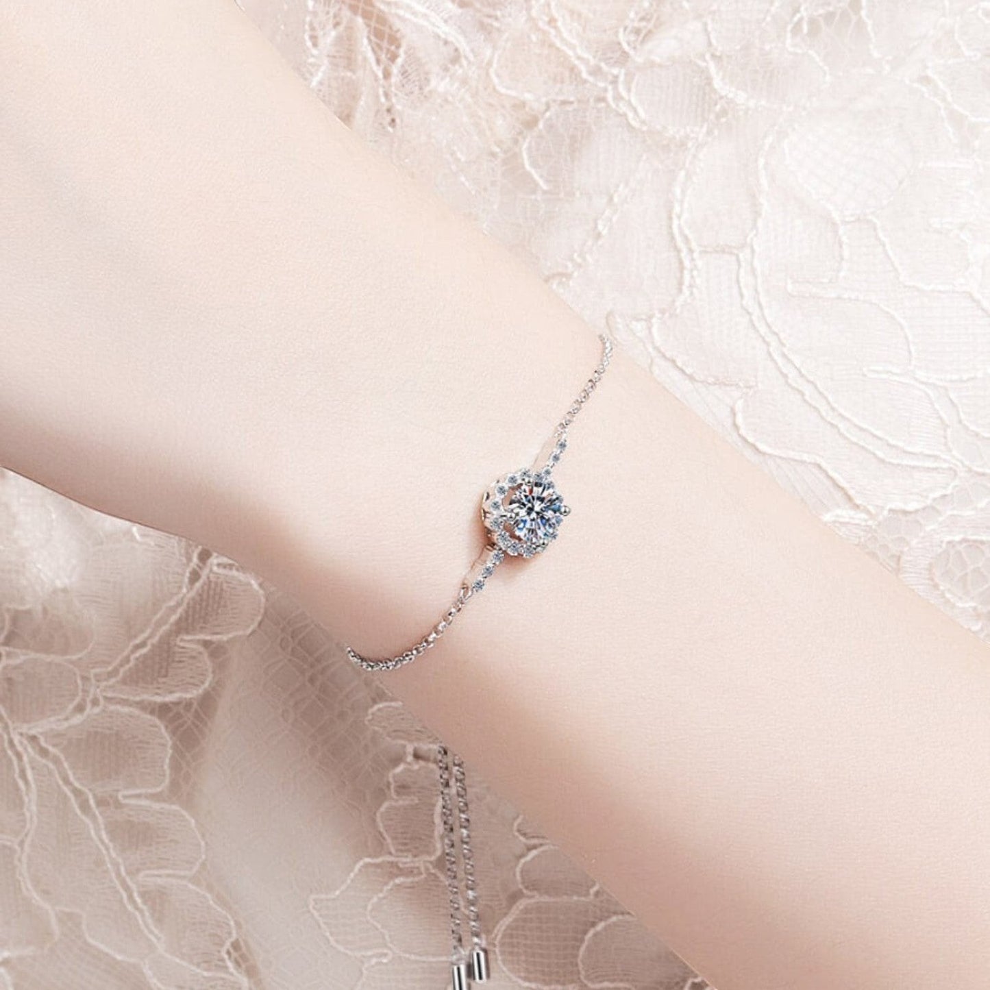 Vooraanzicht van een model dat de luxe ModaMelhor zilveren moissanite armband om de pols draagt tegen een achtergrond van fijn, wit kant.