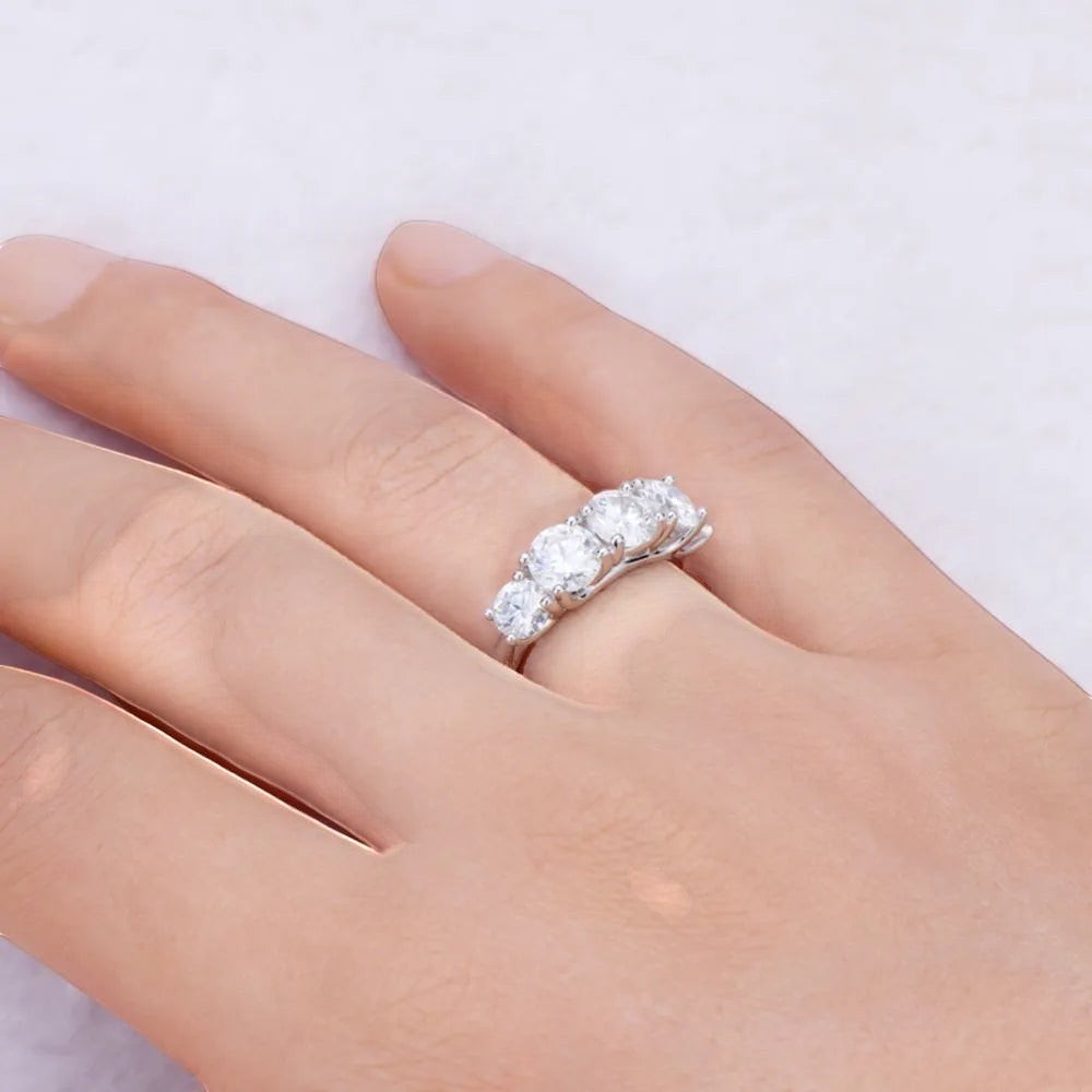 De hand van een model die de luxe ModaMelhor 925 sterling zilveren ring met vijf fonkelende Moissanite stenen elegant draagt.