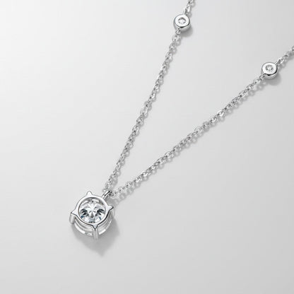 Close-up van de ModaMelhor hanger met een ronde 2 karaat moissanite in een vierpootzetting (4-prong), hangend aan een zilveren ketting met subtiele zirkonia accentsteentjes.