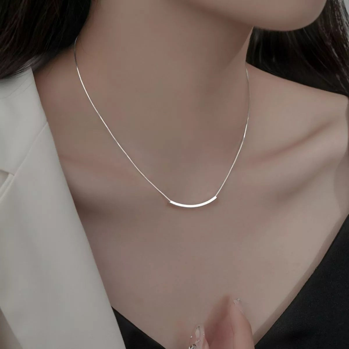Vooraanzicht van een model dat de minimalistische ModaMelhor zilveren ketting met het geïntegreerde, gebogen buisje om de hals draagt.