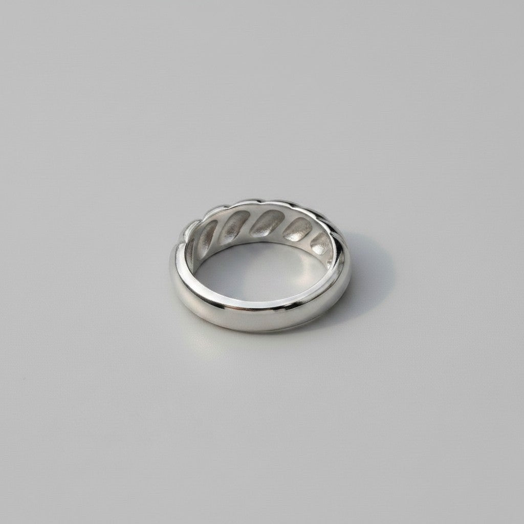 Achteraanzicht van de zilverkleurige ModaMelhor ring van titanium staal, met een focus op de binnenzijde waarin de holtes van het geribbelde ontwerp zichtbaar zijn.