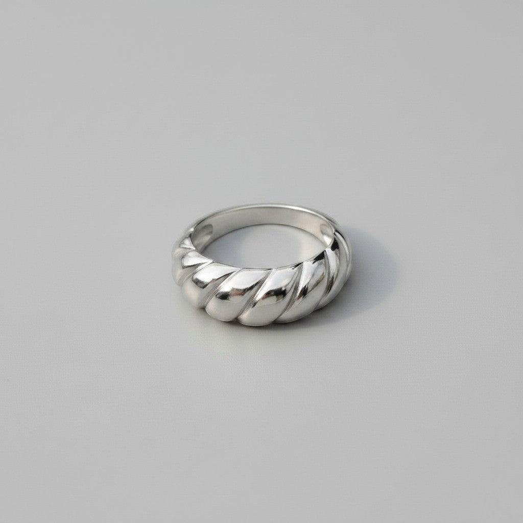 Liggend vooraanzicht van de zilverkleurige ModaMelhor ring van titanium staal, die het glanzende en gedraaide geribbelde patroon duidelijk laat zien.