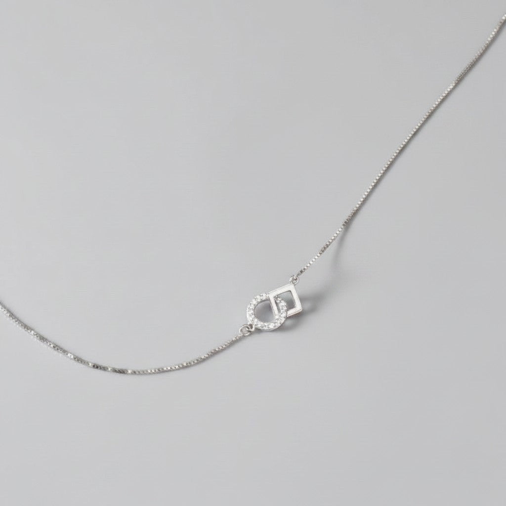 Overzicht van de ModaMelhor zilveren ketting met een geometrische hanger van een in elkaar gehaakt glad vierkant en een met zirkonia bezette cirkel.