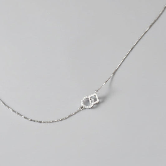 Overzicht van de ModaMelhor zilveren ketting met een geometrische hanger van een in elkaar gehaakt glad vierkant en een met zirkonia bezette cirkel.