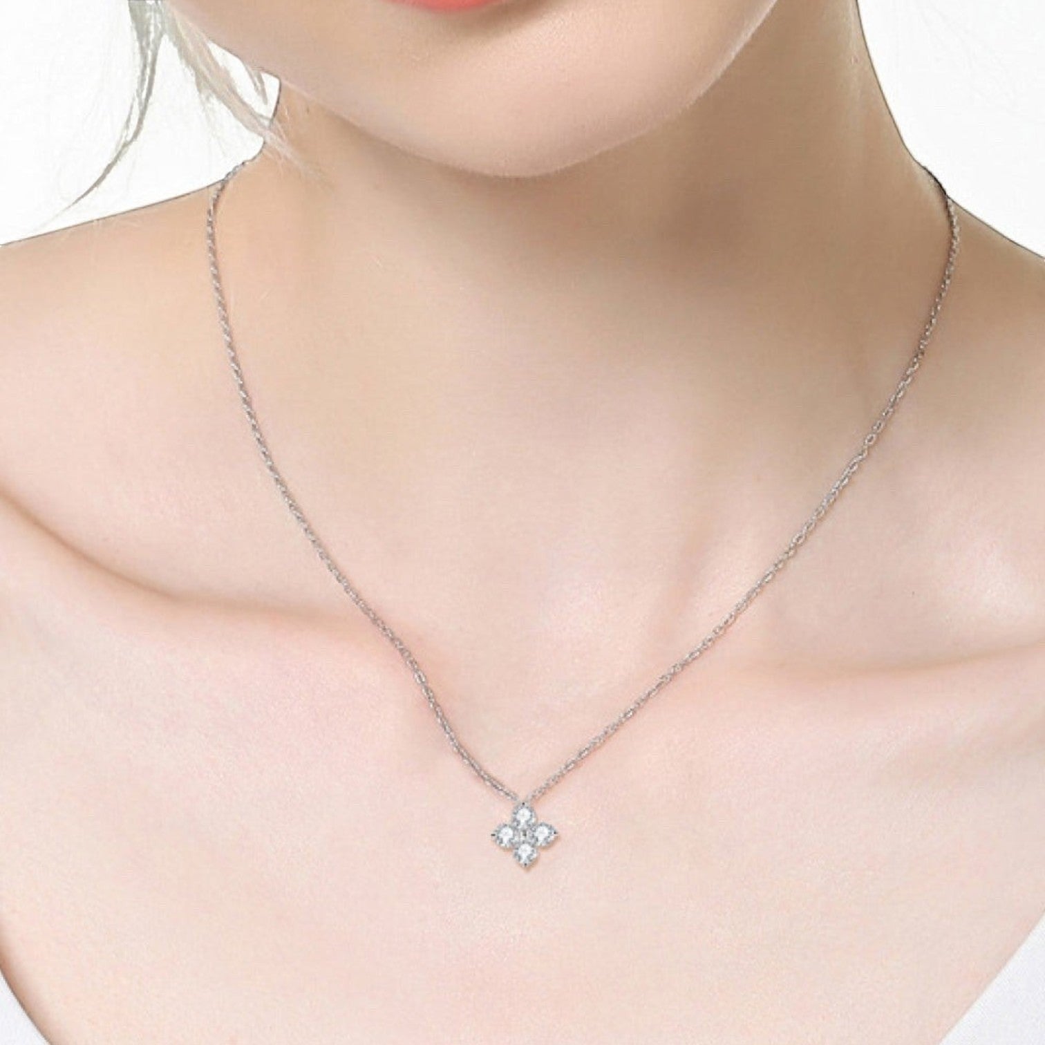 Vooraanzicht van een model dat de zilverkleurige ModaMelhor 925 sterling zilveren ketting met de minimalistische klaverblad hanger om de hals draagt.