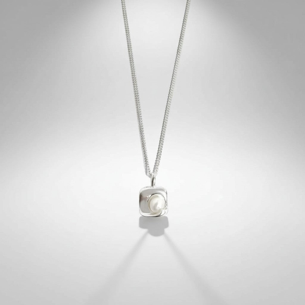Gedetailleerd vooraanzicht van de ModaMelhor hanger van 925 sterling zilver met een modern, vierkant frame waarin een glanzende zoetwaterparel is ingelegd.