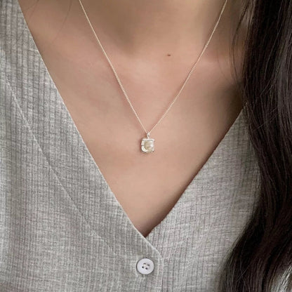 Vooraanzicht van een model dat de zilveren ModaMelhor ketting met de moderne, vierkante zoetwaterparel hanger om de hals draagt.