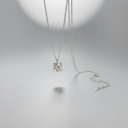 Overzicht van de ModaMelhor zilveren ketting met een moderne, vierkante hanger waarin een ronde zoetwaterparel centraal is geplaatst.