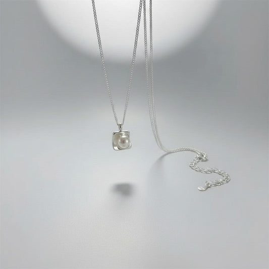 Overzicht van de ModaMelhor zilveren ketting met een moderne, vierkante hanger waarin een ronde zoetwaterparel centraal is geplaatst.