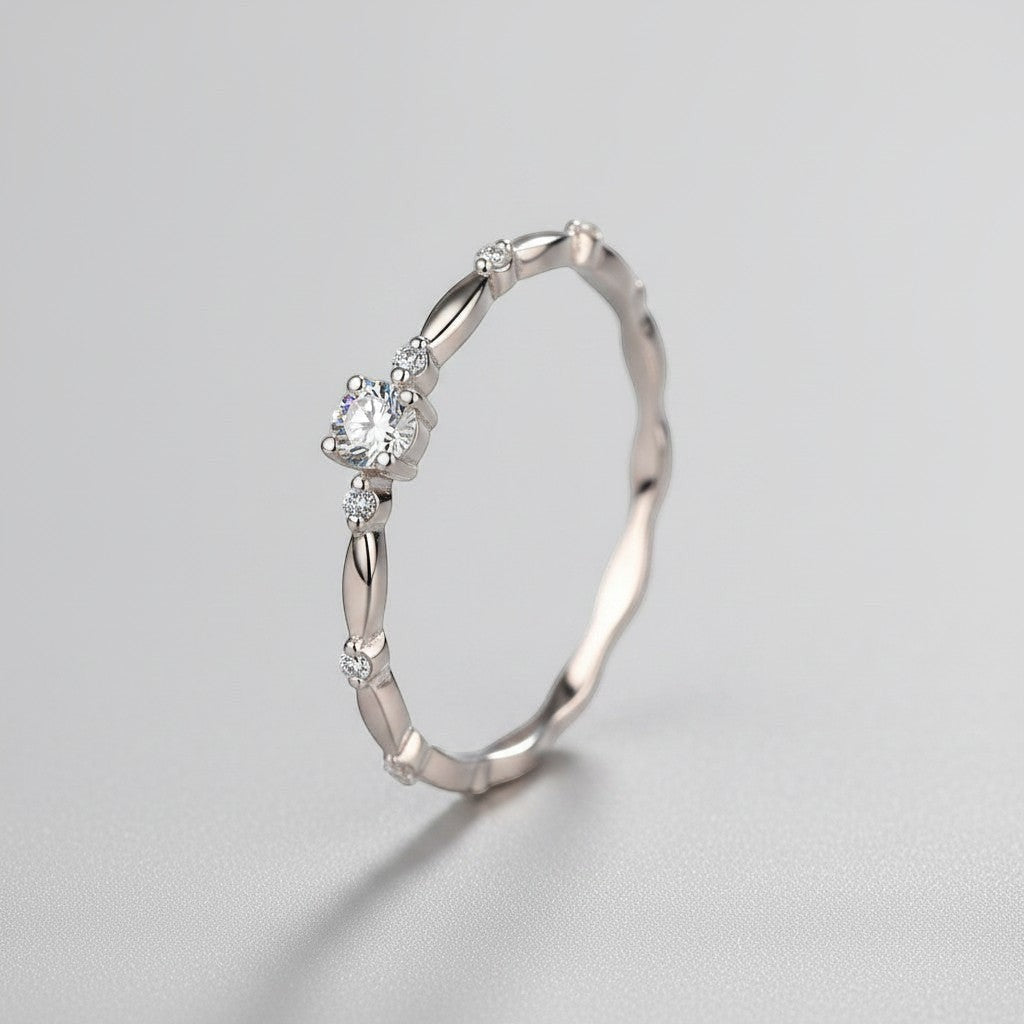 Schuin vooraanzicht van de ModaMelhor zilveren solitair ring, die het verfijnde golvende patroon en de schittering van de ronde moissanite steen prachtig toont.