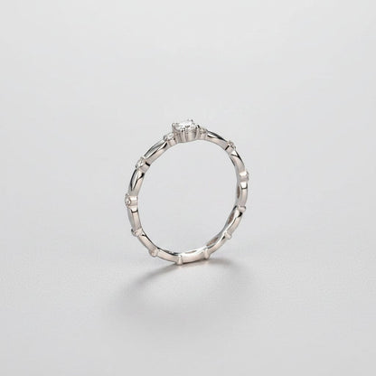 Zijaanzicht van de ModaMelhor zilveren solitair ring, waarbij de verhoogde zetting van de moissanite en het golvende patroon van de band goed te zien zijn.