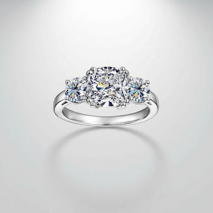 Recht vooraanzicht van de luxe ModaMelhor ring van platina op 925 sterling zilver, met een focus op de kussengenslepen Moissanite hoofdsteen en de twee ronde zijstenen.