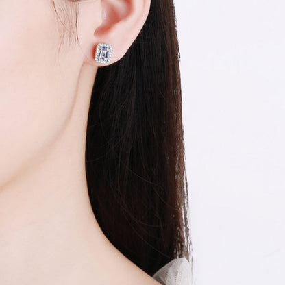 Zijaanzicht van een model die het zilveren ModaMelhor rechthoekige oorknopje met moissanite en een omringende halo van zirkonia in het oor draagt.