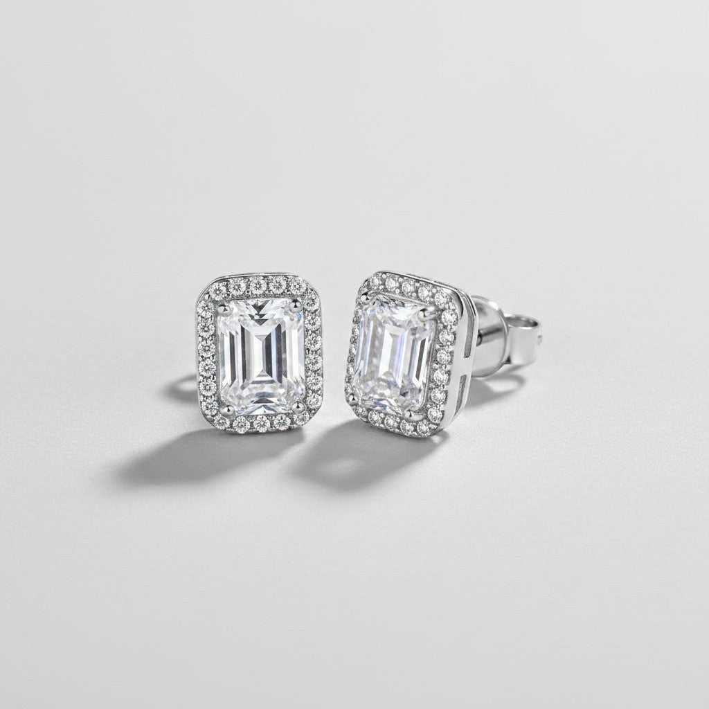 Vooraanzicht en zijaanzicht van de platliggende ModaMelhor rechthoekige oorknopjes van 925 sterling zilver met moissanite stenen en een geometrische halo van zirkonia.