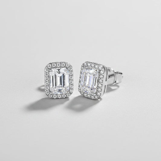 Vooraanzicht en zijaanzicht van de platliggende ModaMelhor rechthoekige oorknopjes van 925 sterling zilver met moissanite stenen en een geometrische halo van zirkonia.