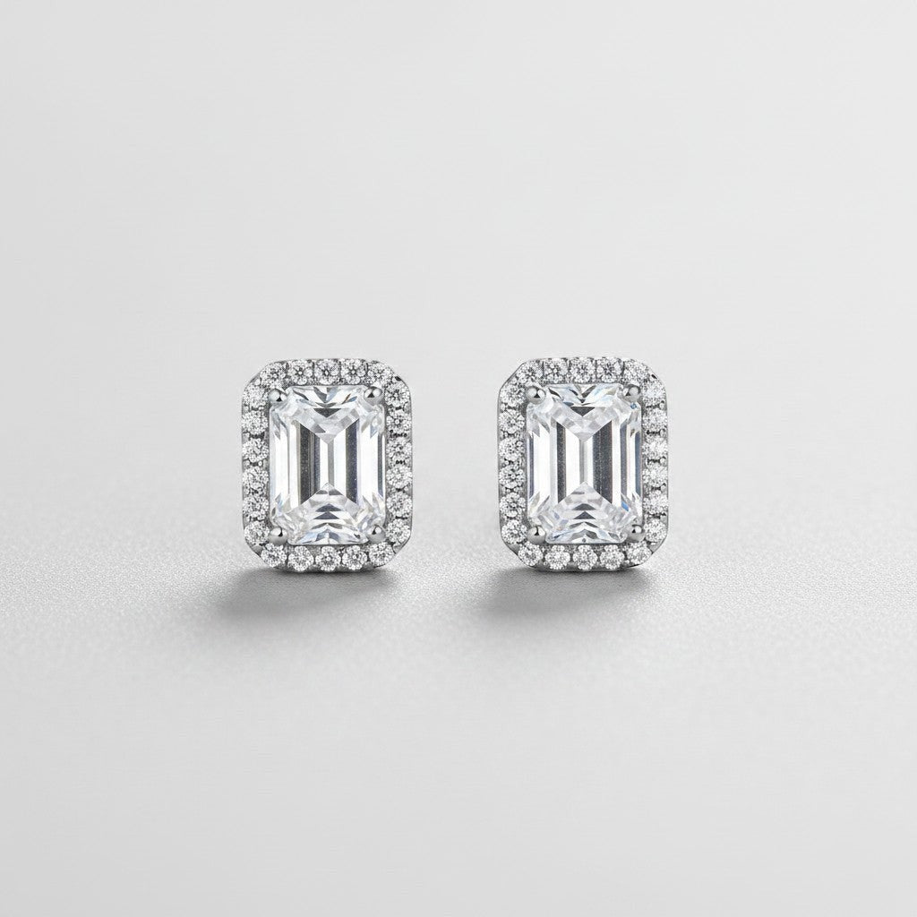 Symmetrisch vooraanzicht van het paar rechtopstaande ModaMelhor rechthoekige oorknopjes van 925 sterling zilver met 1 karaat moissanite stenen en een halo van zirkonia.
