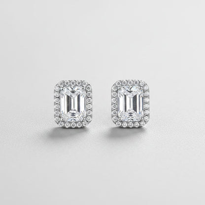 Symmetrisch vooraanzicht van het paar rechtopstaande ModaMelhor rechthoekige oorknopjes van 925 sterling zilver met 1 karaat moissanite stenen en een halo van zirkonia.