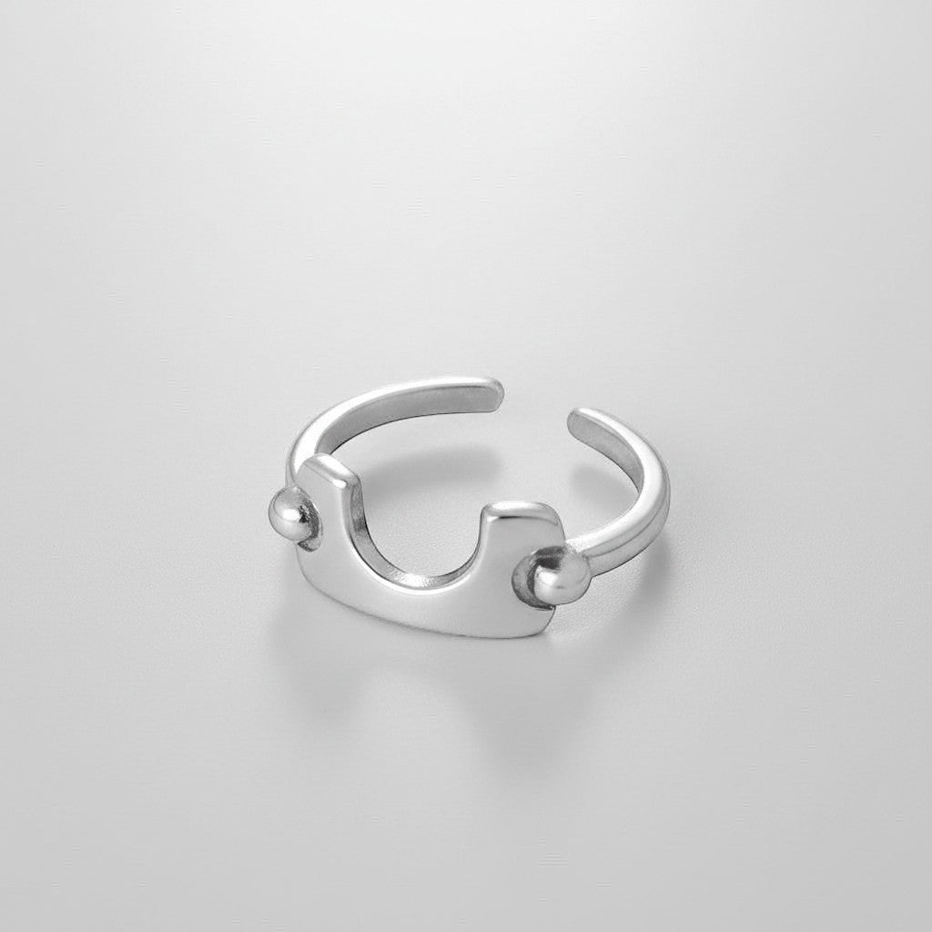 Bovenaanzicht van de ModaMelhor zilverkleurige titanium stalen ring, waarbij het geometrische design aan de voorkant en de open achterkant duidelijk zichtbaar zijn.