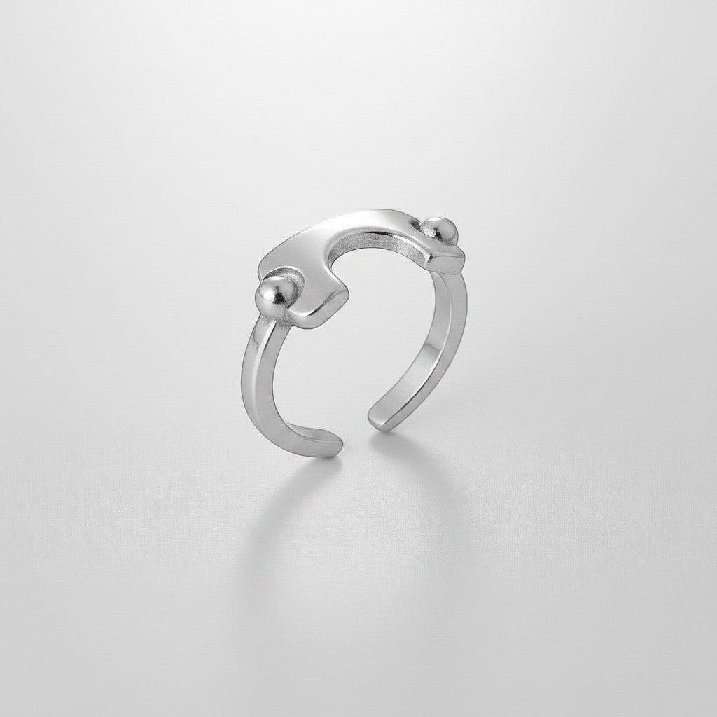 Schuin vooraanzicht van de ModaMelhor zilverkleurige open ring van titanium staal, met een focus op het geometrische design en de bolvormige details.