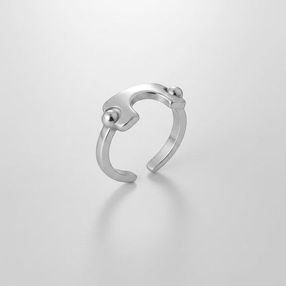 Schuin vooraanzicht van de ModaMelhor zilverkleurige open ring van titanium staal, met een focus op het geometrische design en de bolvormige details.