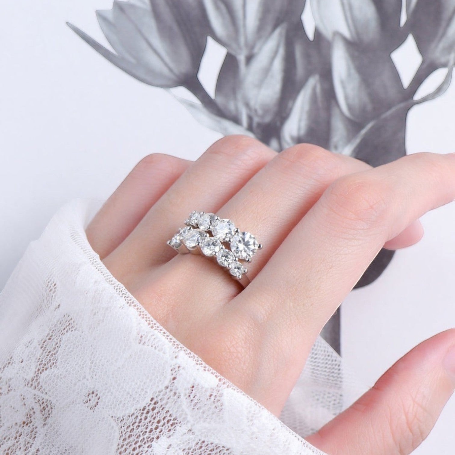 De hand van een model die de ModaMelhor zilveren statement ring met een luxe, dubbele rij van moissanite stenen elegant draagt.