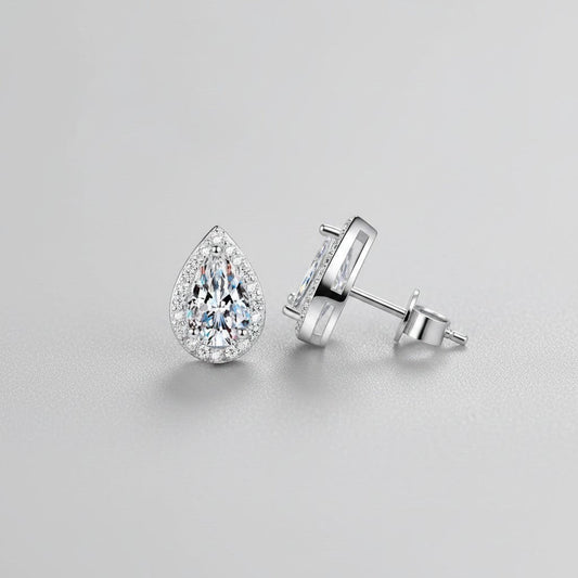 Vooraanzicht en zijaanzicht van de platliggende ModaMelhor druppelvormige oorknopjes van 925 sterling zilver met centrale moissanite stenen en zirkonia accenten.