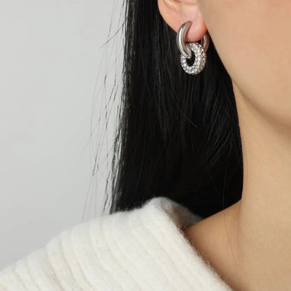Zijaanzicht van een model dat de zilveren ModaMelhor zirconia titanium double hoop oorbel in het oor draagt met de focus op de twee verbonden ringen.
