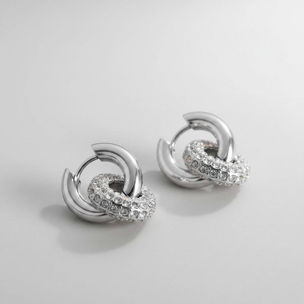 Vooraanzicht van de twee rechtopstaande ModaMelhor zirconia titanium double hoop oorbellen van zilverkleurig titanium met de focus op de glanzende ringen.