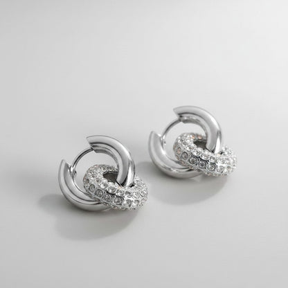 Vooraanzicht van de twee rechtopstaande ModaMelhor zirconia titanium double hoop oorbellen van zilverkleurig titanium met de focus op de glanzende ringen.